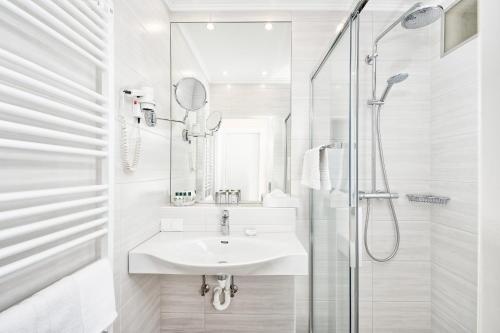 a white bathroom with a sink and a shower at Hotel Schönruh in Drobollach am Faakersee