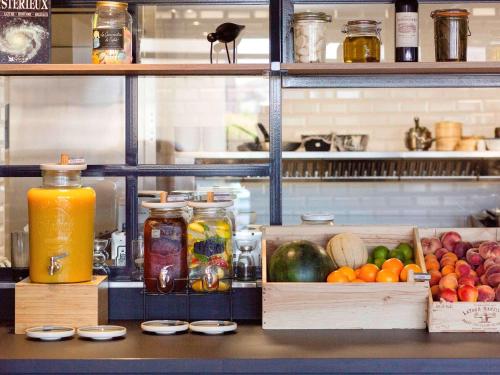 un comptoir avec caisses de fruits et légumes et pots de jus dans l'établissement Novotel Bordeaux Centre Ville, à Bordeaux