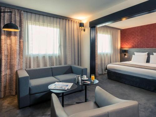 a hotel room with a bed and a couch at Mercure Paris Porte de Pantin in Pantin