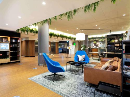 eine Lobby mit blauen Stühlen und einer Couch in der Unterkunft Novotel The Hague World Forum in Den Haag