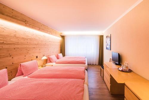 ブリエンツにあるホテル ヴァイセス クロイツのベッド4台とテレビが備わる客室です。