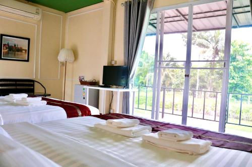 Habitación de hotel con 2 camas y ventana grande. en สวนจันท์วาส รีสอร์ท - Suan Chanthwad Resort, en Chanthaburi