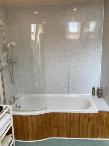 a bathroom with a tub with a glass shower at Stonewater House Vegan Bed and Breakfast in Lamlash