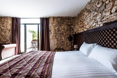 a bedroom with a bed and a stone wall at Le Trésor des Templiers in Malataverne