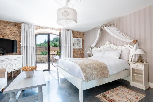a bedroom with a white bed and a large window at Le Trésor des Templiers in Malataverne