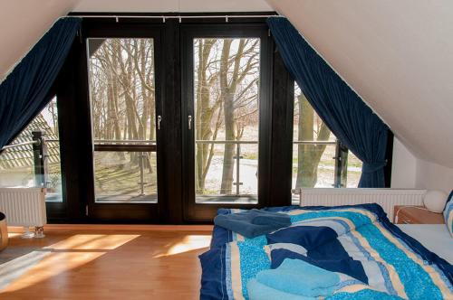 ein Schlafzimmer mit Fenstern und ein Bett mit einer blauen Decke in der Unterkunft Ferienhaus Plau am See, direkt am Wasser in Plau am See