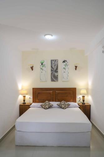 a bedroom with a large white bed with two lamps at ilamparuma Hotel in Weligama