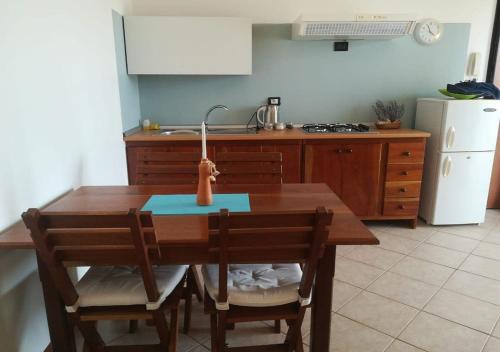 cocina con mesa de madera, 2 sillas y fregadero en Pedra do Sol Praia Estoril Sal Rei FREE WI-FI, en Sal Rei