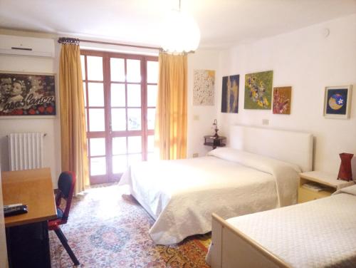 a bedroom with two beds and a desk and a window at Villa Corrias in Siliqua