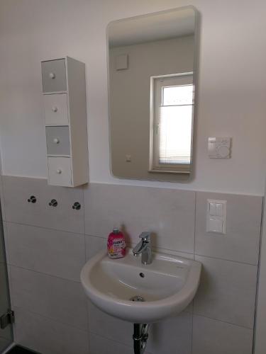 a white bathroom with a sink and a mirror at Ferienwohnung Langgöns in Langgöns