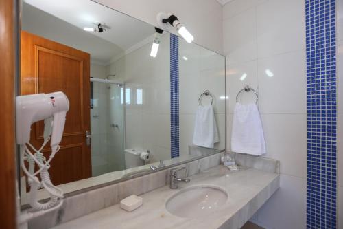baño con lavabo y espejo grande en Pousada Praia Do Meio, en Torres