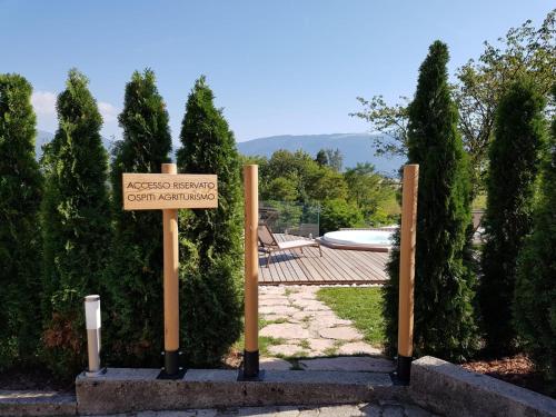 a sign in front of a garden with a pool at AGRITURISMO La Giasena in Ponte nellʼAlpi