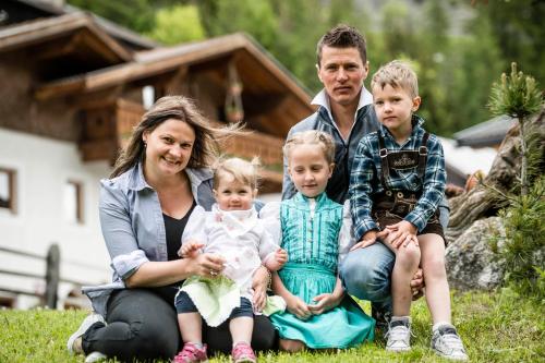 a family sitting on the grass in front of a house at Unterlutaschg-Chalet Appartement am Hof in Slingia