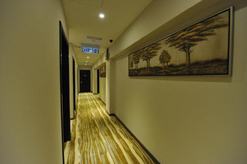 a hallway with a painting of trees on the wall at Milano Hotel in Kluang
