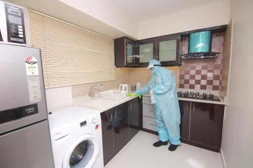 a person standing in a kitchen with a washing machine at Casa Allay in Cochin