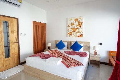 a bedroom with a large white bed with blue pillows at The Reef Resort in Koh Kradan