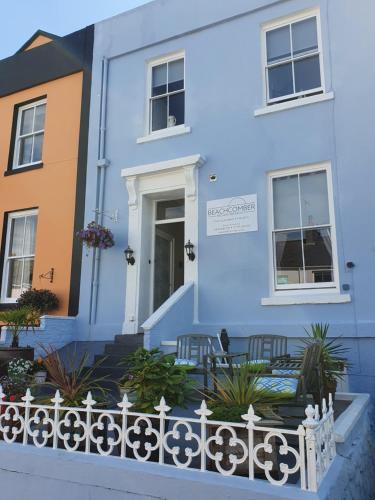 uma casa azul com duas cadeiras em frente a ela em Beachcomber B&B em Tenby