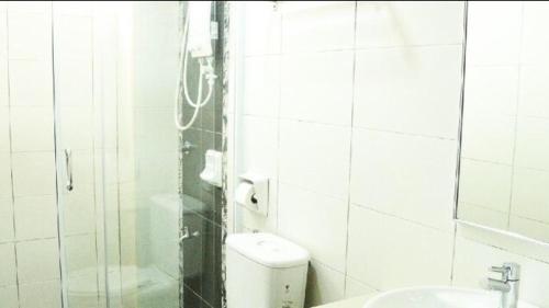 a white tiled bathroom with a toilet and a sink at Marina Height Seaview Resort, Teluk Batik, Lumut in Kampong Tebing Rabak
