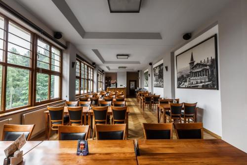 a row of tables and chairs in a room with windows at Parkhotel Smržovka in Smržovka