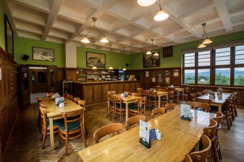 a restaurant with wooden tables and chairs and green walls at Parkhotel Smržovka in Smržovka