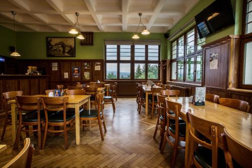 a restaurant with wooden tables and chairs and windows at Parkhotel Smržovka in Smržovka
