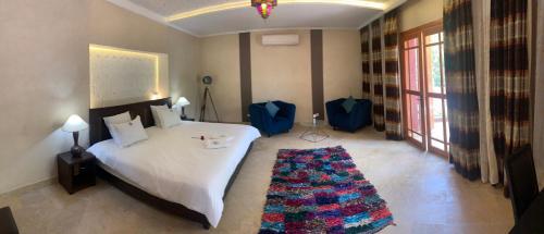 a bedroom with a white bed and a large window at LES JARDINS DE MARRAKECH in Marrakech