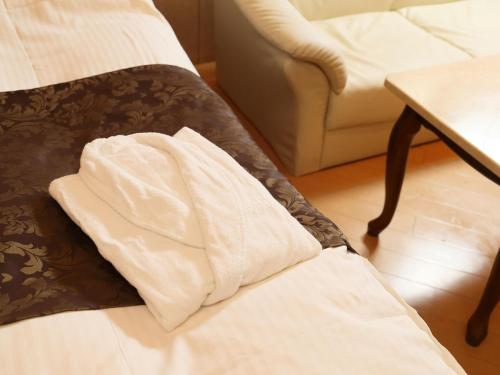 a white blanket sitting on the edge of a bed at Hotel Fine Rokko Kita Ichibanchi in Kobe
