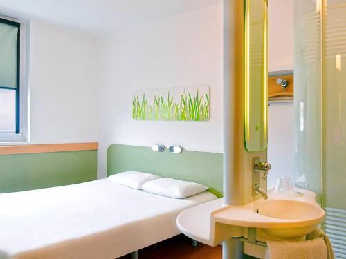 Habitación pequeña con cama y lavamanos en Ibis Budget Grenoble Sud Seyssins, en Seyssins