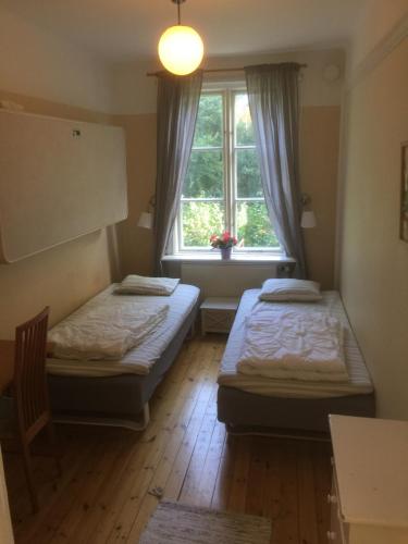 two beds in a room with a window at Tvetagårdens Vandrarhem in Södertälje