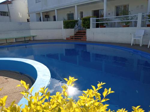 a blue swimming pool in front of a house at Hotel La Posta del Dayman in Termas del Daymán
