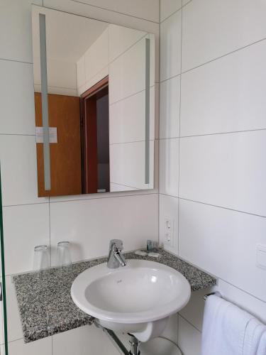 a white bathroom with a sink and a mirror at Appartis - Hotel am Stadtpark in Sindelfingen