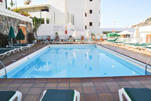 a swimming pool at a hotel with chairs and a building at Bungalow montecarlo 35 and 45 first row with air conditioning&WI-FI and sound insulation in Puerto Rico de Gran Canaria