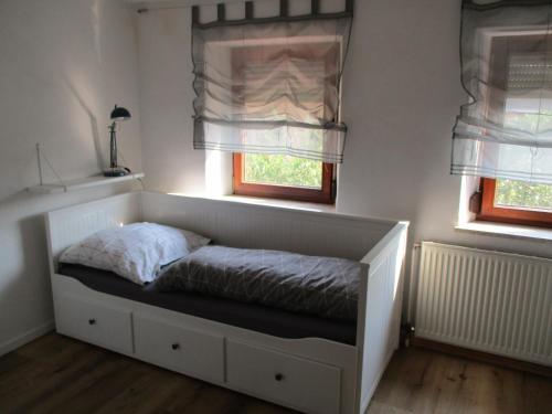 a bed in a room with two windows at Ferienwohnung Rösch in Feuchtwangen