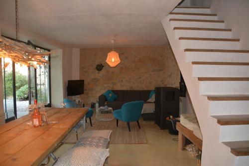 a living room with a wooden table and a staircase at Mas Renard in Beauvoisin