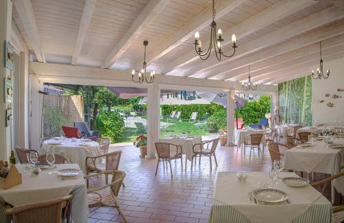 uma sala de jantar com mesas e cadeiras brancas em Hotel Sette Archi em Bocca di Magra