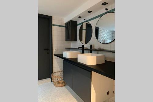 a bathroom with two sinks and two mirrors at Uccle, Pavillon Vert in Brussels