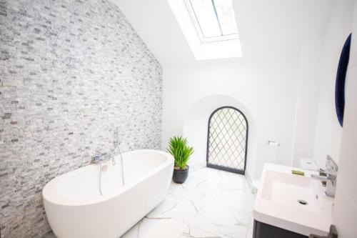 a white bathroom with a tub and a sink at Old Village Hall in Nenthorn