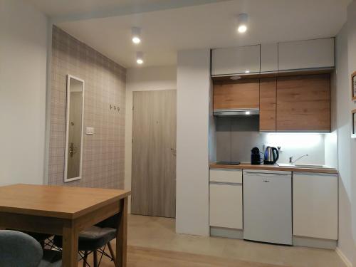 a kitchen with white cabinets and a wooden table at City Apartments Warszawska in Zgorzelec