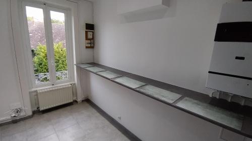 une cuisine blanche avec un comptoir et une fenêtre dans l'établissement La Batisse de Saint-Chamond ( chambres ), à Saint-Chamond