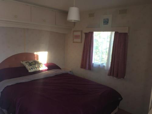 um pequeno quarto com uma cama e uma janela em The Sanctuary 20 sandgate, south road,NR29 4JH, Hemsby em Hemsby