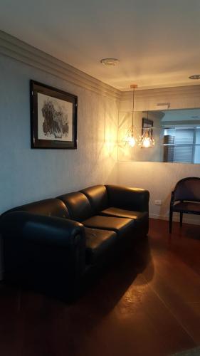 a living room with a leather couch in a room at Ótimo apartamento no Centro mobiliado e com garagem in Curitiba