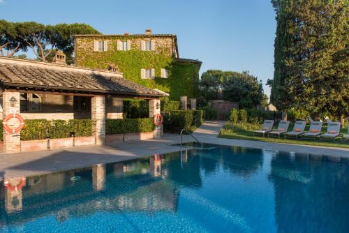 - une piscine avec des chaises à côté d'un bâtiment dans l'établissement Borgo San Felice, à Castelnuovo Berardenga