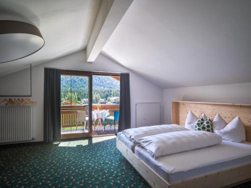 ein Schlafzimmer mit einem großen Bett und einem Balkon in der Unterkunft Design Apartments & Zimmer - Zugspitze in Leutasch