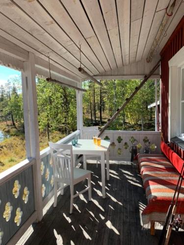 a screened in porch with a white table and chairs at Wilderness and Calmness in Lapland in Nattavaara