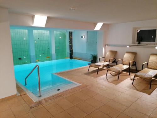 una gran piscina con sillas y una mesa en una habitación en Adler Hotel-Pension, en Fulpmes