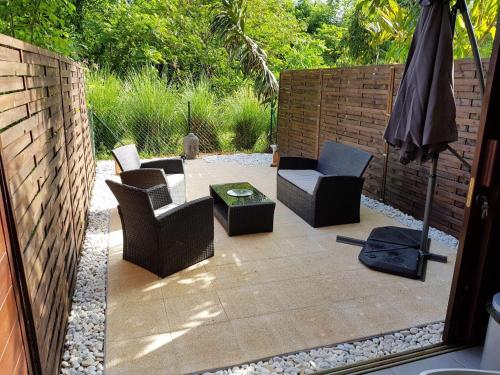 a patio with chairs and a table and an umbrella at studio meublé Montjoly avec accès piscine in Rémire-Camp