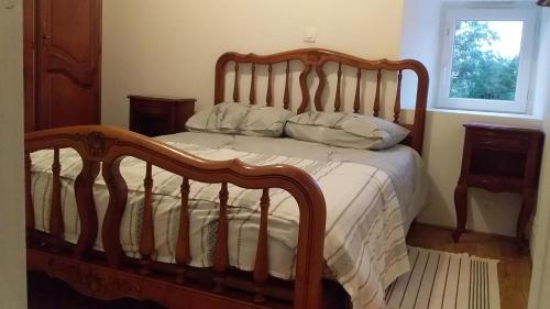 um quarto com uma cama de madeira com lençóis e almofadas brancos em Ferme Maya em Saint-Genest-Lerpt