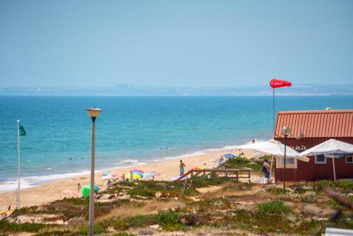 a beach with a building and people on the beach at Blife Sun Hostel & Rooms in Faro