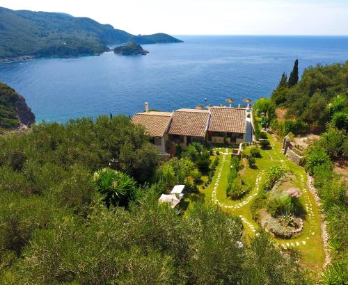 eine Luftansicht eines Hauses auf einem Hügel neben dem Wasser in der Unterkunft Bouganville in Paleokastritsa