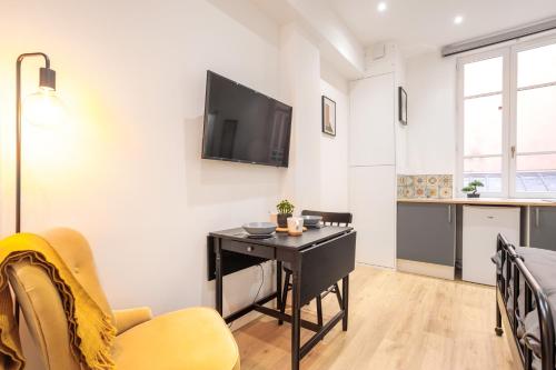 un salon avec une table et une télévision au mur dans l'établissement Lumignons Lyonnais - Vaise, à Lyon